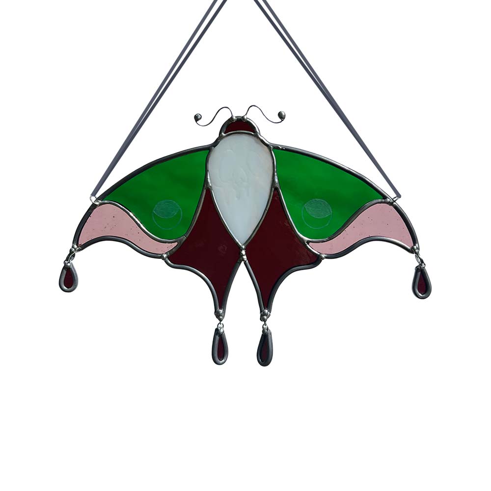 Stained glass moth decoration with green, pink, and white colors on a white background