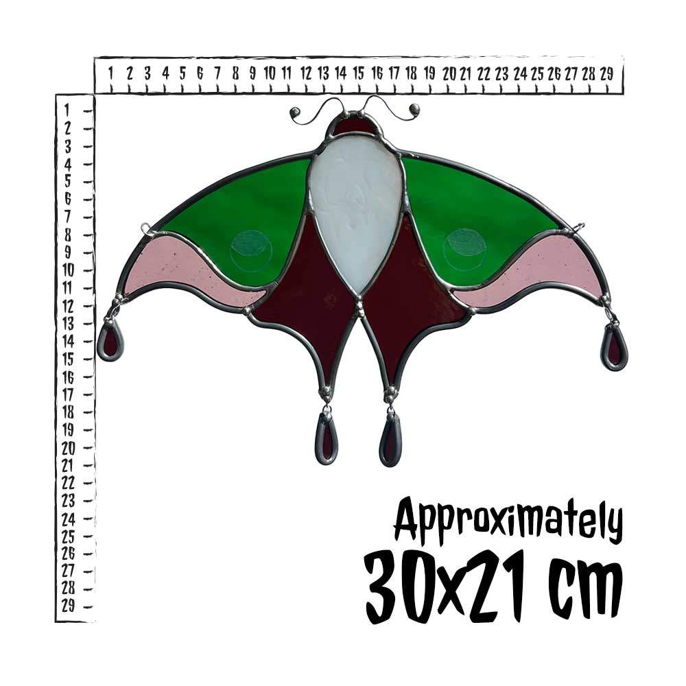 Decorative stained glass moth with a ruler for scale on a white background