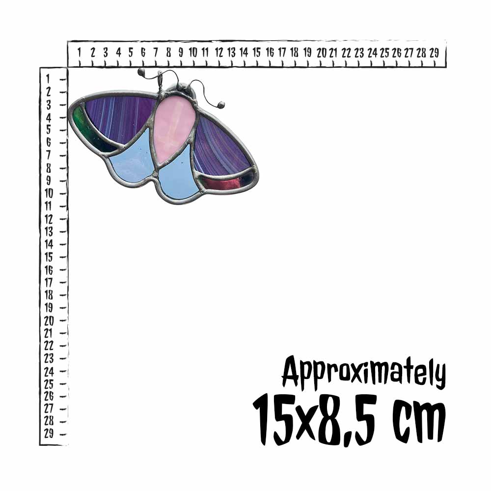 Moth-shaped stained glass piece with a ruler for scale on a white background