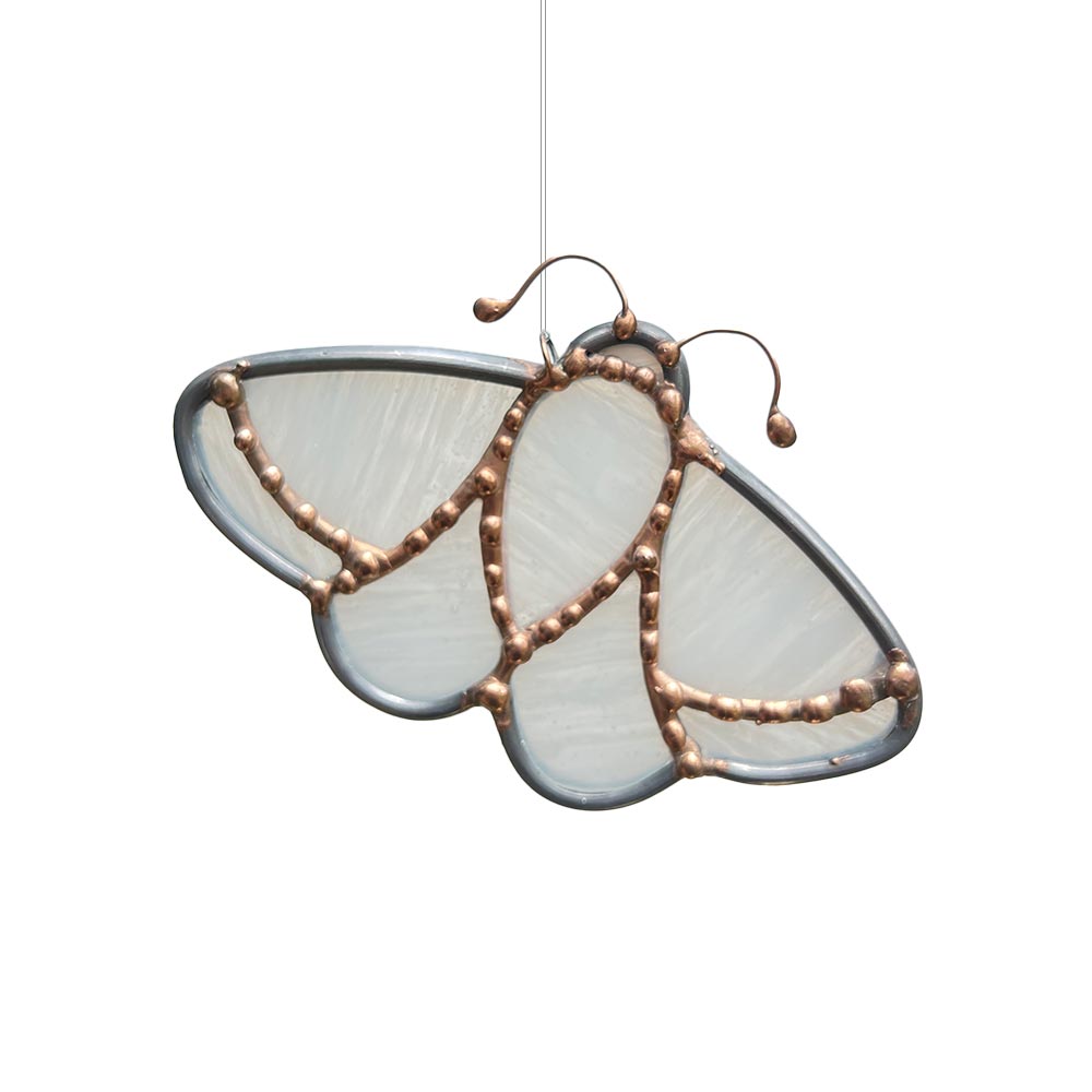 Delicate white stained glass moth with copper accents and engraved cross, handcrafted decorative window ornament for interiors.